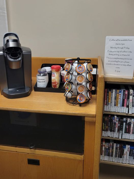 A Keurig coffee maker with a variety of k-cups and other coffee accessories sitting on a shelf.